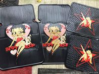 Four rubber mats laid out showing Betty Boop designs, two with Betty Boop and dog inside heart shapes and two with Betty Boop sitting inside a star shape.