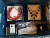 Container holding red glass bead necklace, black resin bib necklace, jewelry boxes and gold-tone wristwatch