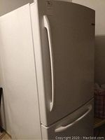 Front view of white Moffat refrigerator with top door and bottom drawer