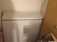 Closed view of the white chest freezer from the front showing smooth top lid and rectangular shape.