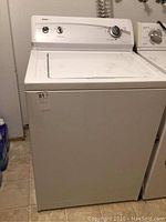 Front view of the Kenmore top loading washer showing the overall white exterior and mechanical control panel at the back with three knobs.