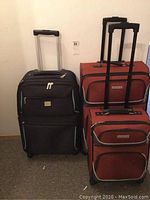 Three rolling luggage cases: one black Liz Claiborne case and two brown Air Canada cases with telescoping handles.
