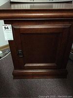 Front view of the wooden cabinet with closed door showing dark wood finish and metal handle