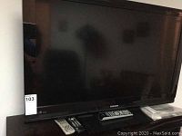 Full view of Toshiba 40 inch television showing flat screen and included remote controls on the stand below.