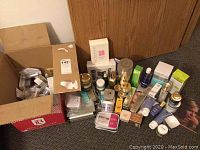 Wide view of cardboard box and assorted beauty product boxes, jars and bottles on carpet