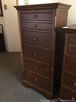 Front view of tall dark brown wooden dresser showing six drawers