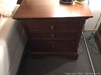 Front view of wooden nightstand showing three drawers and top surface
