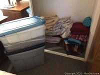 Storage bins and folded textiles including quilts and rugs in a small closet area