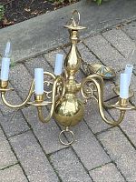 Full view of the solid brass chandelier showing the five arms and decorative central column.