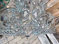 Top down close-up image showing the detailed scrollwork and floral patterns as well as the lattice border and central classical column motif on the metal decorative panel.