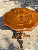 Full view of the wooden side table with floral wood inlay on octagonal top and pedestal base with three legs.