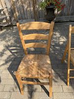 Front view of wooden chair with cane seat and three-slat backrest.