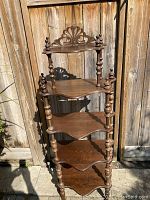 Front view showing entire wooden knickknack stand with carved decorations and finials