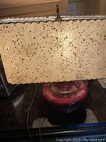 Lamp turned off showing the red ceramic glaze base and rectangular shade with retro pattern