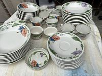Overview of stacked bowls, plates, cups, and saucers on cloth surface