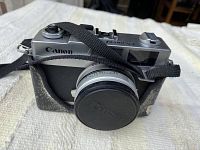Front view of the Canon Canonet 28 camera with strap and lens cap attached, showing Canon branding.