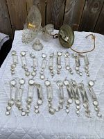 19 crystal strands with hanging cut crystal pieces and metal rings laid out together with a Bohemia crystal fixture including lighting socket and glass parts.