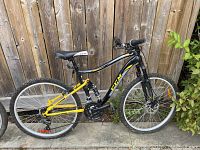 Full side view of the yellow and black CCM Static bike showing frame, chain, pedals, seat, handlebars and wheels.