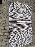 Full view of the multicolor striped runner laid flat showing fringed ends and horizontal stripes in multiple colors including blues, reds, whites.