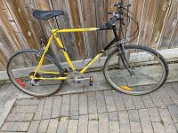 Side view of yellow and black hybrid bike showing frame, wheels, pedals, seat, and handlebars