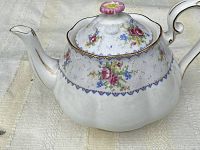 Close-up of Royal Albert Petit Point teapot showing floral pattern and gold trim, visible repair on spout tip.