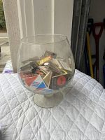 Clear brandy snifter glass filled with assorted vintage matchbooks.