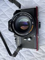 Close-up front view of Minolta MC Rokkor-PF 50mm f/1.7 lens mounted on XE-7 camera body.