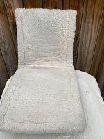 Photo of the fluffy white wool side of the car seat warmer cushion, showing its soft texture.