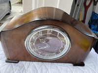 Front view of vintage wooden mantel clock showing face, hands, and overall wood casing with curved top.