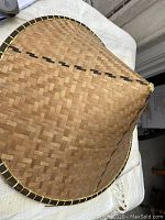Photo clearly showing the traditional woven bamboo conical hat with black trim and stitch details.