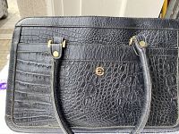 Front view of black crocodile-embossed leather purse with gold-tone hardware and straps