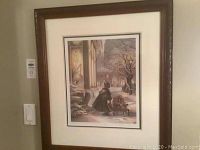 Full view of framed print on wall showing dark wood frame and matting