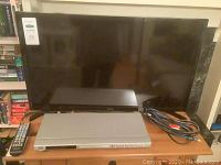 Samsung 31-inch TV with JVC DVD player on shelf, includes remote and cables