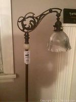 Full view of lamp showing ornate top arm, glass bell shade and marble base