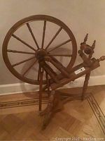 Full side view of wooden spinning wheel showing drive wheel and flyer assembly
