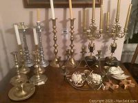 Overview of all candlesticks, candelabras, decorative holders and candles on a table.