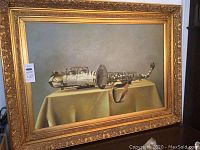 Full view of framed painting of a saxophone lying on a table with a golden ornate frame.