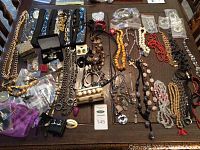 Overview of entire table with assorted necklaces, bracelets, earrings, pendants