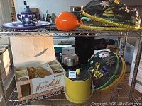 Shelf shot showing beverage set box with pitcher handle visible, yellow ice bucket with black lid next to it, and other miscellaneous items around.