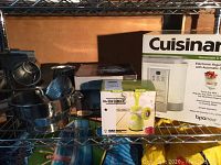 Shelf display with original boxed Cuisinart yogurt maker, Raw Grinder meat mincer box, and metal pasta machine parts.