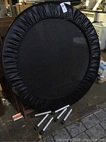 Front view of circular rebounder frame with black jumping mat and padded vinyl cover