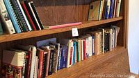 Bookshelves filled with assorted cookbooks including various sizes and binding types