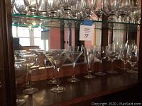 Shelf with assorted stemware including martini glasses, wine glasses, champagne flutes, water goblets all clear glass.