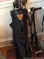 Black soft cover travel golf bag with emblem on pocket.