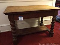 Full view of the solid oak table showing carved spiral legs and lower shelf.