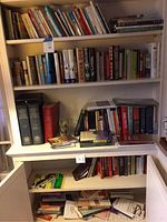 Bookshelves and cabinet with a variety of hardbound and softbound books in multiple genres including mystery, history, biographies, religious, fiction, and nonfiction.