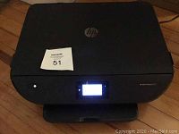 Front view of the HP Envy Photo 6255 printer showing the power button and digital display screen lit up.
