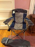 Front view of the assembled Northwest Territory folding camping chair with the matching carrying bag placed beside it.