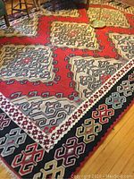 Top view of the woven wool area rug displaying the geometric central pattern with red background and surrounding smaller motifs.