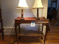 Full view of the wooden occasional table with two lamps on top, showing size and design.